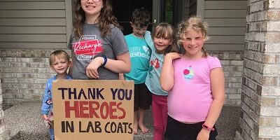 Children holding sign that says Thank You Heroes in Lab Coats Children holding sign that says Thank You Heroes in Lab Coats